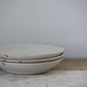 Stack of pale stoneware plates on a rustic wooden tabletop