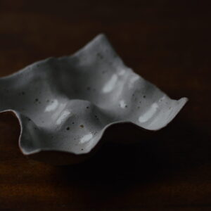 Stoneware, moulded egg holder suitable for four eggs, shown on a dark wooden table.
