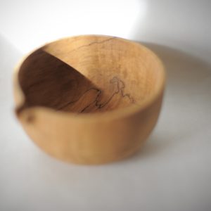 a hand carved wooden pouring bowl with an ultra smooth finish. Photographed against an all white background with a shaft of daylight shining across it.