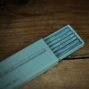A light blue slide-out box containing six drawing pencils which are embossed with key words relating to the Visual Arts: Aesthetic Avant-garde Bricolage Sentimentality Sublime Sfumato