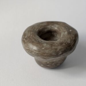 A mushroom shaped, hand moulded and unfired clay vessel.