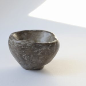 A hand moulded, unfired clay bowl