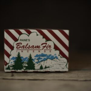 Small box with red and white candy stripe. Showing a mountain landscape with fir trees in foreground with the name Balsam Fir.