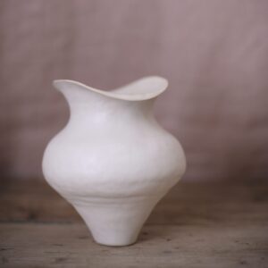 White bulbous vase shown against a plaster pink background